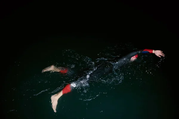 Атлет триатлона плавает в темную ночь в гидрокостюме — стоковое фото