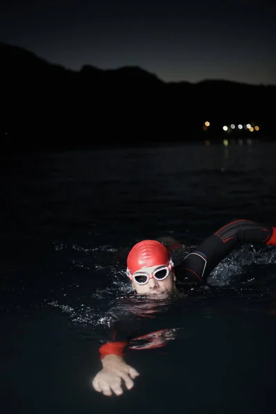 Triathlet schwimmt in dunkler Nacht im Neoprenanzug — Stockfoto