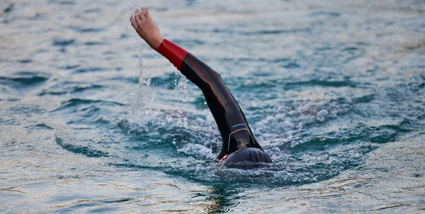 Triatlon atleet zwemmen op meer in zonsopgang het dragen van wetsuit — Stockfoto