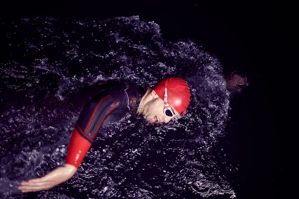 Triathlet schwimmt in dunkler Nacht im Neoprenanzug — Stockfoto