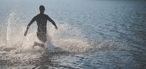 Triathlon athlete starting swimming training on lake — Stock Photo, Image