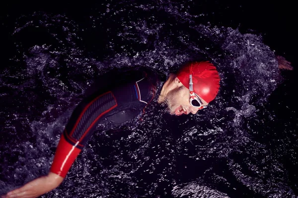 Atleta de triatlón nadando en la noche oscura usando traje de neopreno —  Fotos de Stock