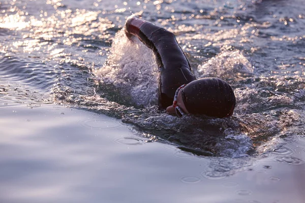 Triathlon idrottare simma på sjön i soluppgången bär våtdräkt — Stockfoto