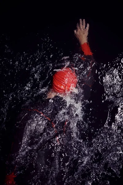 Atleta triatlo nadando na noite escura vestindo roupa de mergulho — Fotografia de Stock