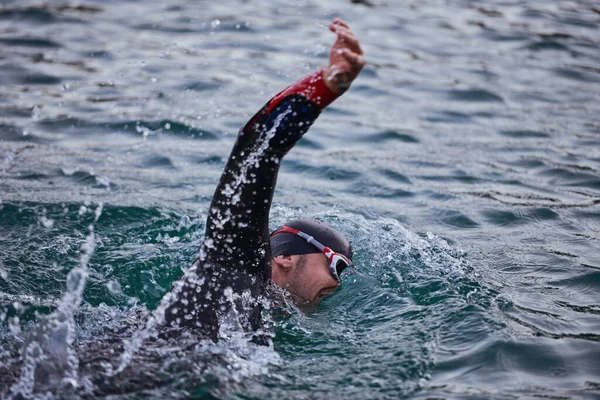 Atleta de triatlón nadando en el lago al amanecer usando traje de neopreno —  Fotos de Stock