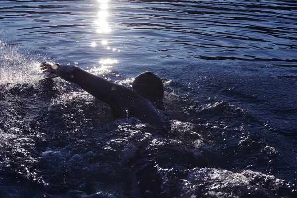 Triathlon idrottare simma på sjön i soluppgången bär våtdräkt — Stockfoto