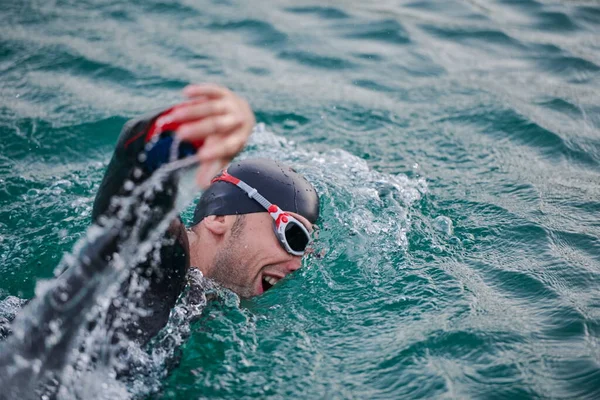 Triatlon atleet zwemmen op meer in zonsopgang het dragen van wetsuit — Stockfoto