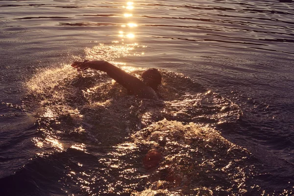 Triathlon athlete swimming on lake in sunrise wearing wetsuit — Stock Photo, Image