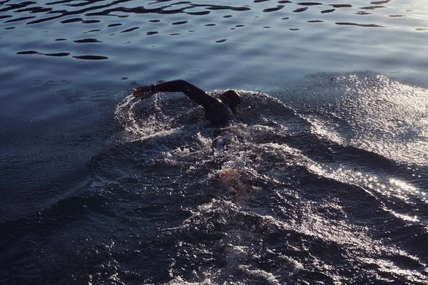 Triathlon idrottare simma på sjön i soluppgången bär våtdräkt — Stockfoto