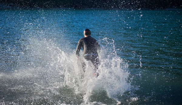 Спортсмен тріатлону починає тренування з плавання на озері — стокове фото