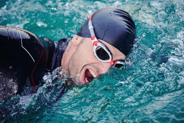 Triatlon sporcusu gün doğumunda gölde yüzüyor. Dalgıç kıyafeti giyiyor. — Stok fotoğraf