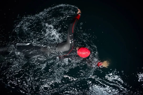 Triatlon atlet plavání v tmavé noci na sobě neoprén — Stock fotografie