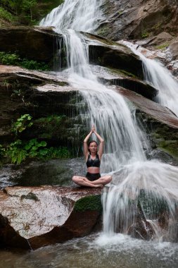 Nilüfer çiçeğinin altında oturan genç kadın sakin bir güçle meditasyon yapıyor ve doğal enerji sükuneti ve iç denge ile tamamen bağlantılı.