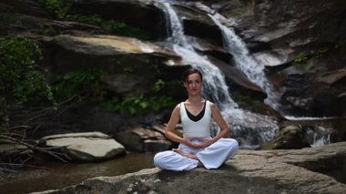 Nilüfer çiçeğinin altında oturan genç kadın, sakin bir güçle meditasyon yapıyor ve doğal enerji sükuneti ve iç denge ile tamamen bağlantılı. Yavaş çekim sinematik çekim