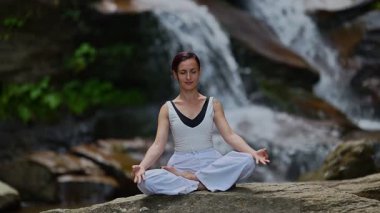 Nilüfer çiçeğinin altında oturan genç kadın, sakin bir güçle meditasyon yapıyor ve doğal enerji sükuneti ve iç denge ile tamamen bağlantılı. Yavaş çekim sinematik çekim