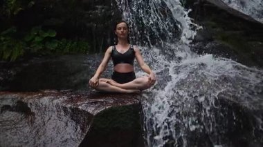 Nilüfer çiçeğinin altında oturan genç kadın, sakin bir güçle meditasyon yapıyor ve doğal enerji sükuneti ve iç denge ile tamamen bağlantılı. Yavaş çekim sinematik çekim