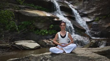 Nilüfer çiçeğinin altında oturan genç kadın, sakin bir güçle meditasyon yapıyor ve doğal enerji sükuneti ve iç denge ile tamamen bağlantılı. Yavaş çekim sinematik çekim