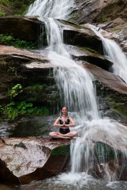 Nilüfer çiçeğinin altında oturan genç kadın sakin bir güçle meditasyon yapıyor ve doğal enerji sükuneti ve iç denge ile tamamen bağlantılı.