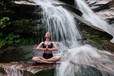 Nilüfer çiçeğinin altında oturan genç kadın sakin bir güçle meditasyon yapıyor ve doğal enerji sükuneti ve iç denge ile tamamen bağlantılı.