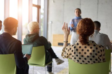 Çeşitli iş adamları modern bir ofiste dikkatle oturup, bir eğitmenin önderliğindeki bir eğitim oturumunda aktif olarak en son teknolojik gelişmelere odaklanırlar.