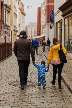 Aileler oğluyla birlikte büyüleyici şehir sokaklarında el ele yürüyorlar mevsimin sıcaklığının tadını çıkarıyorlar ve birlikte neşeli anılar yaratıyorlar.