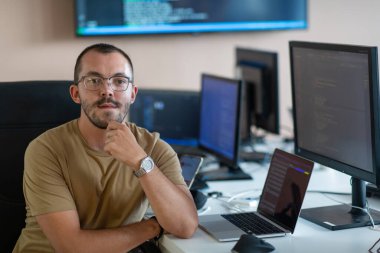 Bir programcı ofisinde otururken akıllı telefon uygulamalarını özenle test eder