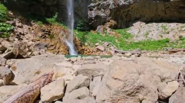 Bereketli yeşil ağaçlar ve ormanlarla çevrili kayalık bir uçurumdan şelalenin havadan çekilmiş videosu güneşli bir yaz gününde FPV insansız hava aracıyla ağır çekimde çekildi..