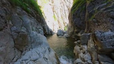 Bereketli yeşil ağaçlar ve ormanlarla çevrili kayalık bir uçurumdan şelalenin havadan çekilmiş videosu güneşli bir yaz gününde FPV insansız hava aracıyla ağır çekimde çekildi..