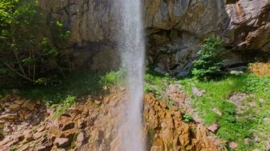 Bereketli yeşil ağaçlar ve ormanlarla çevrili kayalık bir uçurumdan şelalenin havadan çekilmiş videosu güneşli bir yaz gününde FPV insansız hava aracıyla ağır çekimde çekildi..