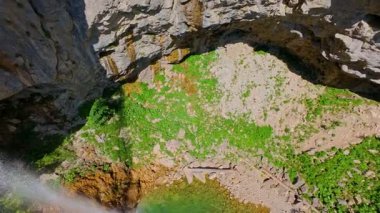 Bereketli yeşil ağaçlar ve ormanlarla çevrili kayalık bir uçurumdan şelalenin havadan çekilmiş videosu güneşli bir yaz gününde FPV insansız hava aracıyla ağır çekimde çekildi..