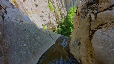 Bereketli yeşil ağaçlar ve ormanlarla çevrili kayalık bir uçurumdan şelalenin havadan çekilmiş videosu güneşli bir yaz gününde FPV insansız hava aracıyla ağır çekimde çekildi..