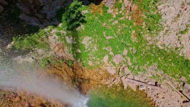 Bereketli yeşil ağaçlar ve ormanlarla çevrili kayalık bir uçurumdan şelalenin havadan çekilmiş videosu güneşli bir yaz gününde FPV insansız hava aracıyla ağır çekimde çekildi..
