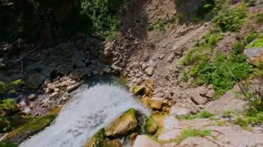 Bereketli yeşil ağaçlar ve ormanlarla çevrili kayalık bir uçurumdan şelalenin havadan çekilmiş videosu güneşli bir yaz gününde FPV insansız hava aracıyla ağır çekimde çekildi..