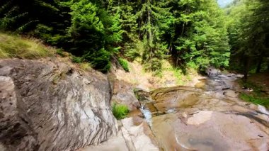 Bereketli yeşil ormanlarda kayaların üzerinden akan güzel bir şelalenin havadan çekilmiş videosu, temiz su akıntısı olan manzaralı doğa manzarası, rahatlama ve macera için gidilecek yer. Sinematik ağır çekim