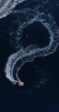 Mavi okyanus suyunda sonsuz döngü oluşturan bir sürat teknesinin yukarıdan aşağıya insansız hava aracı görüntüsü doğadaki özgürlüğü, sonsuzluğu, geleceği ve sonsuz yaz macerasını sembolize ediyor. Dikey video