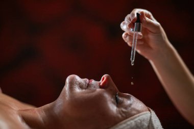 Olgun bir kadının kaplıcada yatarken yüzünün üstünde bir damlatıcıyla cilt bakımı yapan bir terapist. Güzellik ve sağlık konsepti yaşlanmayı önleyici tedavi, su kaybı ve bütünsel