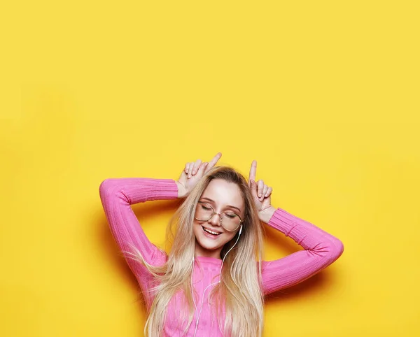 Lifestyle and people concept: Look at me like Im funny. Portrait of a young beautiful girl on a yellow background with a smiling showing horns on the camera. — Stock Photo, Image