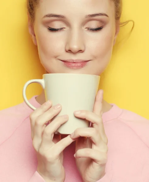 年轻的金发女人拿着白杯子喝茶或咖啡 生活方式和食物的概念 关门了黄色背景 — 图库照片