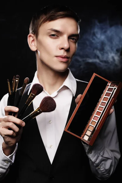 Beauty concept. Young male make up artist posing with make-up brushes and shadow palette — Stock Photo, Image