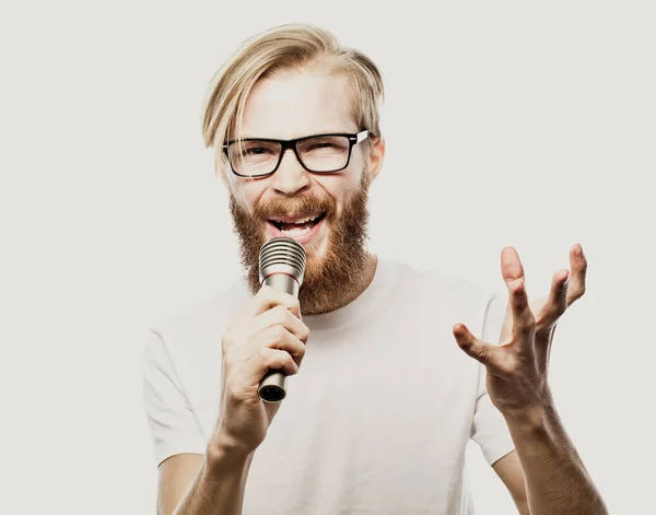 Junge rockt aus. Bild eines gutaussehenden bärtigen Mannes, der ins Mikrofon singt. Emotionales Porträt eines attraktiven Typen mit Bart auf weißem Hintergrund — Stockfoto