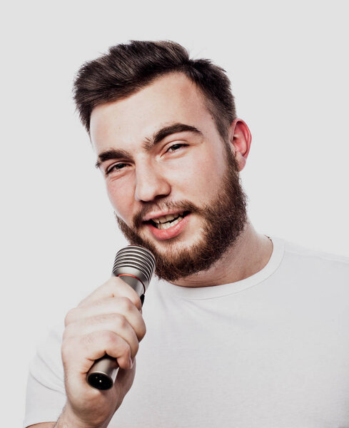 Эстрадник. Молодой говорящий человек держит микрофон, изолированный на белом фоне.
