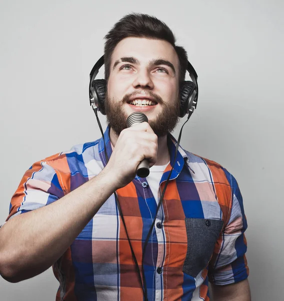 Életmód és emberek koncepció: fiatal férfi énekel mikrofonnal — Stock Fotó