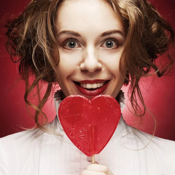 Femme avec coeur caramel sur fond rouge — Photo