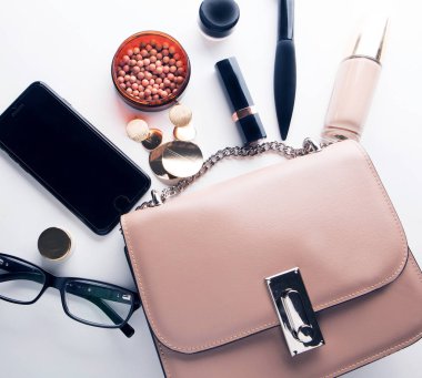 Kozmetik, aksesuarları ve beyaz arka plan kopya alanı ile smartphone ile pembe deri kadın çanta dışarı açık düz göklere.
