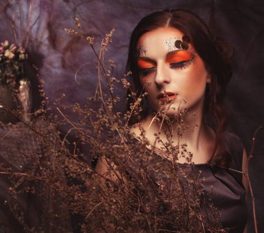 Güzellik ve sanat kavramı: kuru dalları ile parlak makyaj ile genç kadın