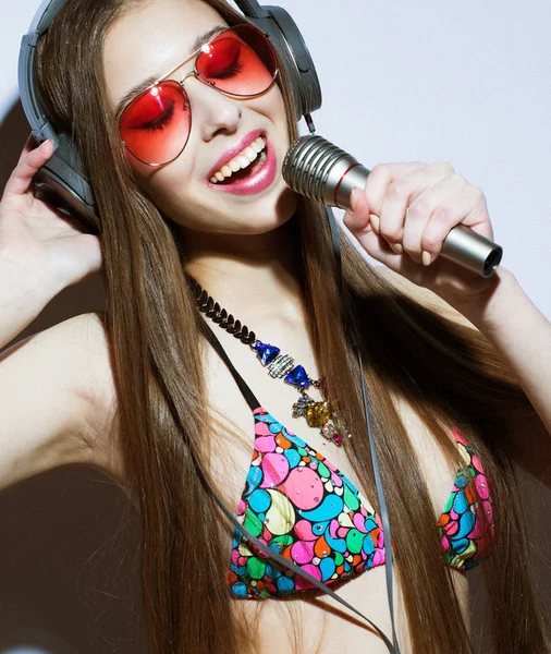 Modelo chica en auriculares con micrófono con traje de baño rosa sobre fondo blanco —  Fotos de Stock