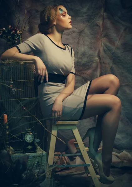 Молода модель моди з креативним макіяжем, що сидить на табуреті — стокове фото