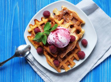 Dondurma ve mavi ahşap arka plan üzerinde taze çilek ile Belçika waffle tabak