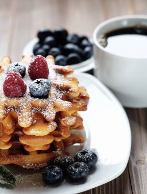 Waffle beyaz plaka ve kahve, çilek ile yakın çekim.