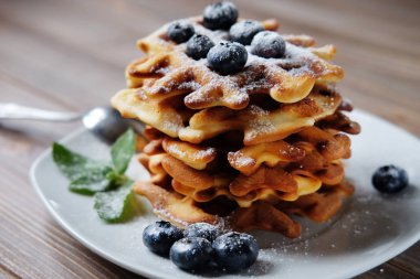 Ahşap arka plan üzerinde taze yaban mersini ve ahududu ile ev yapımı Belçika Waffle.